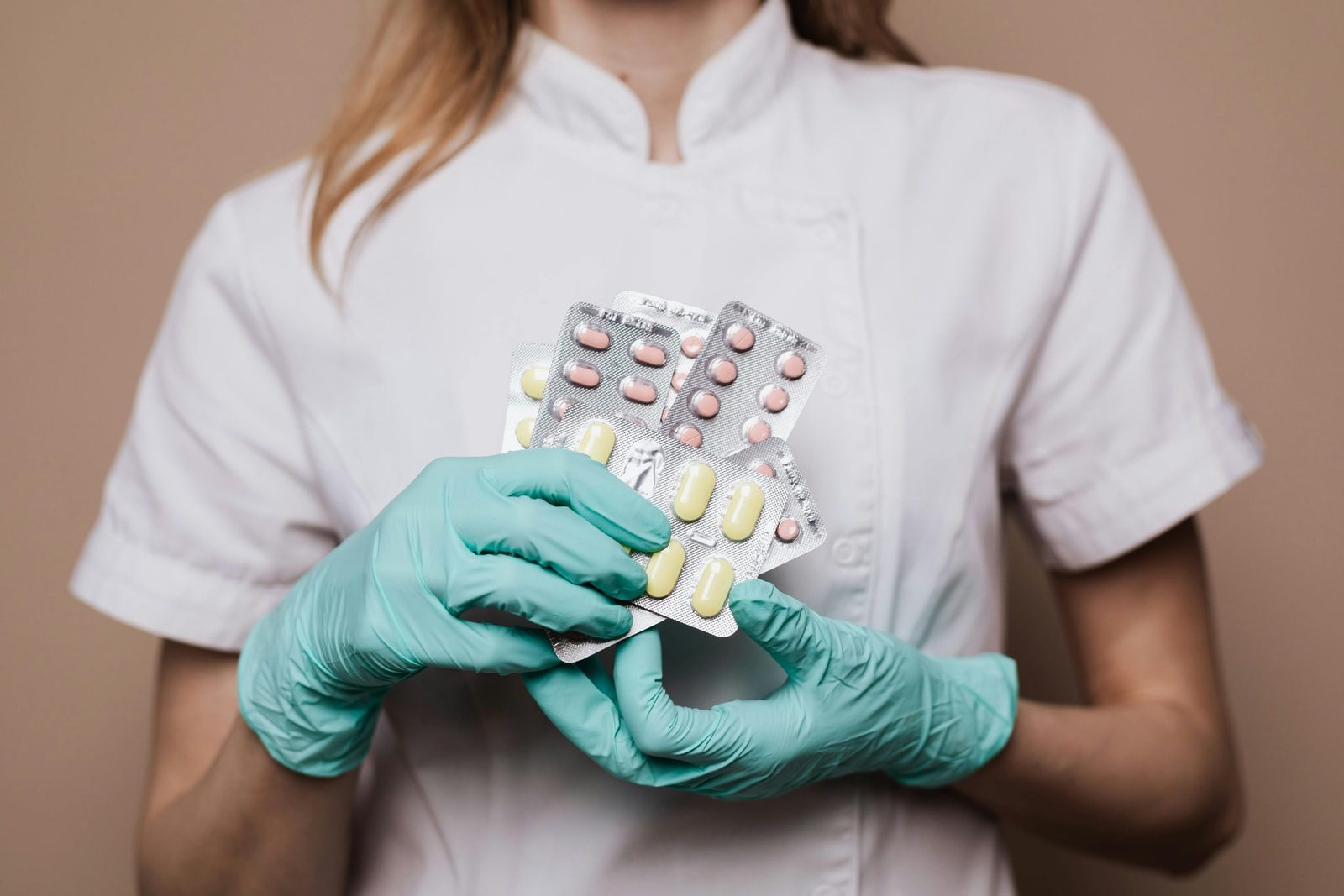 Hände in Handschuhen halten mehrere Tablettenblister